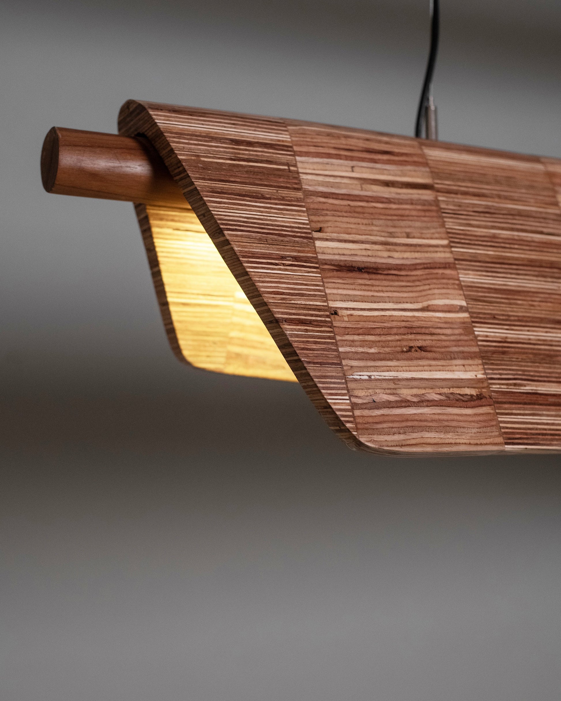 Wooden pendant light with a warm glow on a gray background