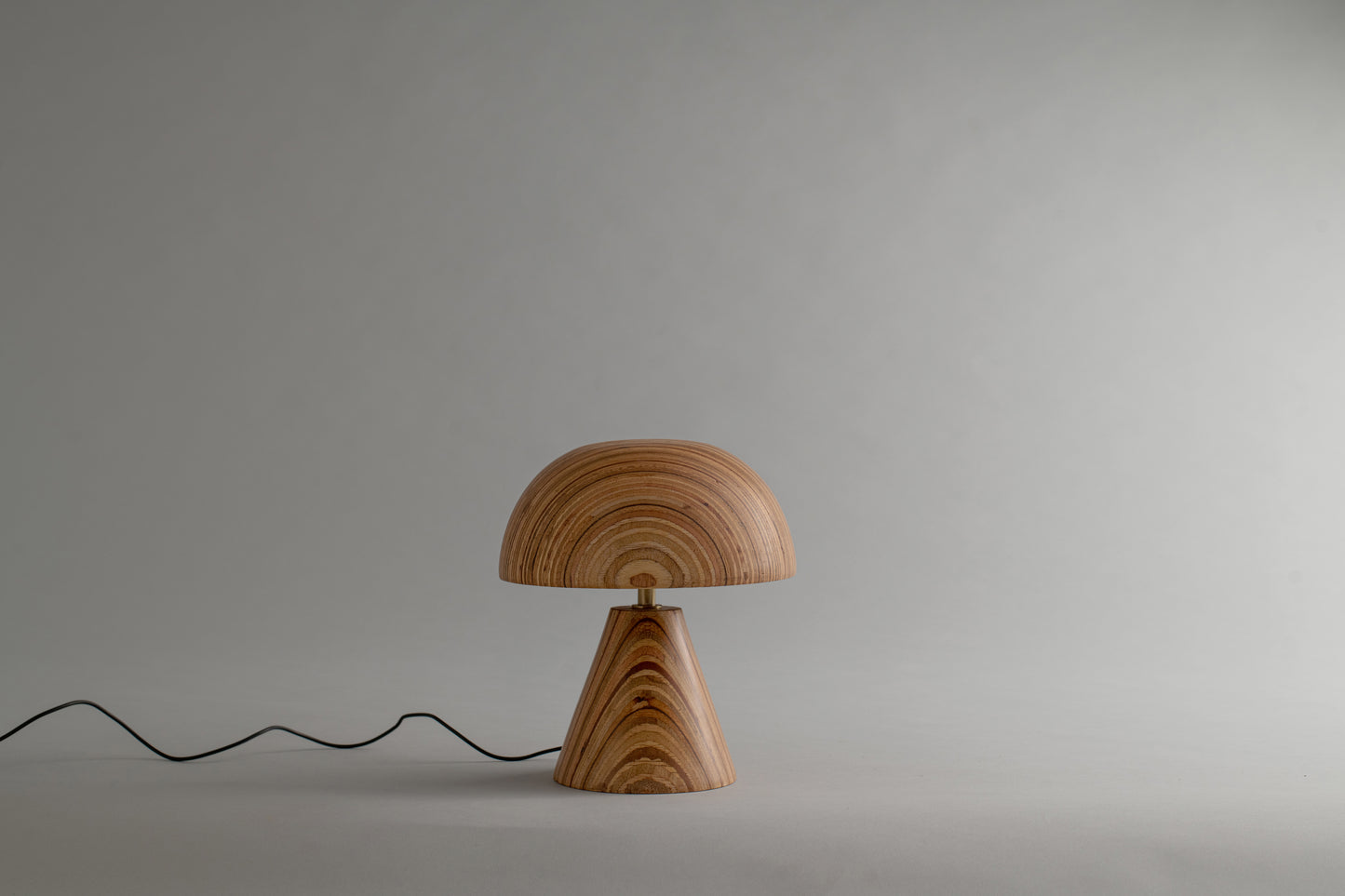 Wooden lamp with a wavy cable on a plain background