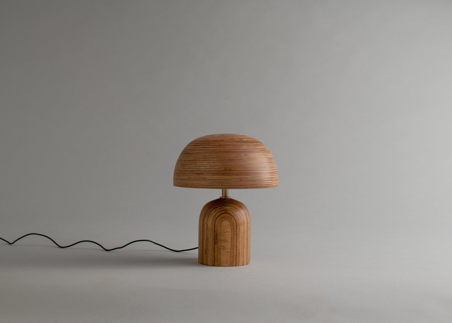 Wooden table lamp with a dome-shaped shade on a plain background